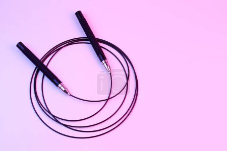 Téléchargez les photos : Noir fitness corde à sauter gros plan isolé sur fond rose. équipement sportif crossfit - en image libre de droit