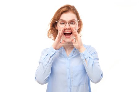 Photo for Portrait of redhead young woman screaming into her palms on white studio background. Important information, news concept - Royalty Free Image