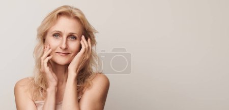 Foto de Hermosa rubia de mediana edad mujer sonriente cara mirando retrato de la cámara Elegante señora madura sin maquillaje 50 años de edad primer plano aislado en blanco - Imagen libre de derechos
