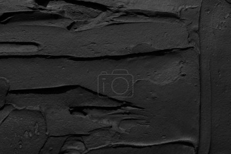 Foto de Fondo decorativo de masilla negra. Textura de pared con pasta de relleno aplicada con espátula, guiones caóticos y trazos sobre yeso. Diseño creativo, patrón de piedra, cemento - Imagen libre de derechos