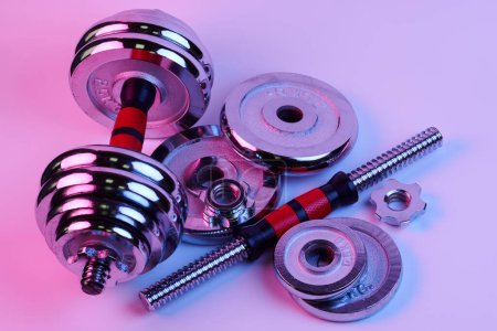 Photo for Metal demountable dumbbells with black plates and red handles isolated on white background in pink lilac light - Royalty Free Image