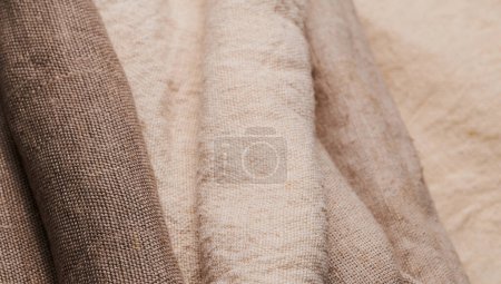 Foto de Ropa de cama en diferentes texturas y colores. Tejidos naturales de lino orgánico y algodón en rollos, textiles hechos a mano. Arpillera y lienzo para decoración ecológica, rústica, boho, hygge - Imagen libre de derechos