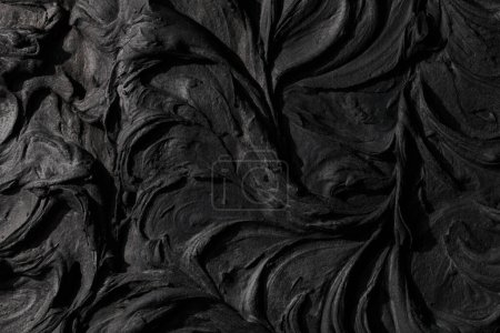 Téléchargez les photos : Décoratif fond de mastic noir. Texture murale avec de la pâte de remplissage appliquée avec une spatule, des tirets chaotiques et des traits sur du plâtre. Conception créative, motif en pierre, ciment - en image libre de droit