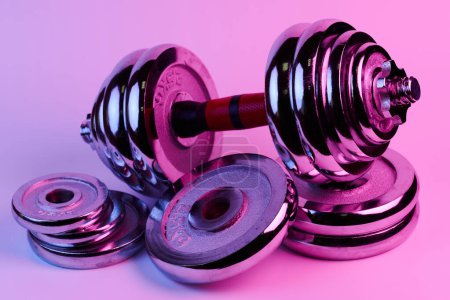 Photo for Metal demountable dumbbell with black plates and red handle isolated on white background in pink lilac light - Royalty Free Image