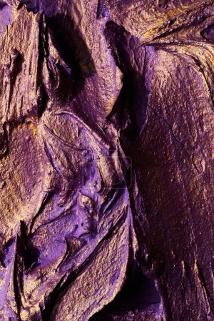 Téléchargez les photos : Décoratif violet fond de mastic d'or. Texture murale avec de la pâte de remplissage appliquée avec une spatule, des tirets chaotiques et des traits sur du plâtre. Conception créative, motif en pierre, hommes - en image libre de droit