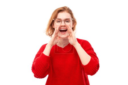 Photo for Portrait of redhead young woman screaming into her palms on white studio background. Important information, news concept - Royalty Free Image