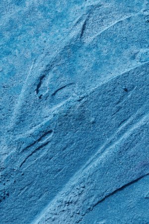 Téléchargez les photos : Décoratif fond de mastic bleu. Texture murale avec de la pâte de remplissage appliquée avec une spatule, des tirets chaotiques et des traits sur du plâtre. Conception créative, motif en pierre, hommes - en image libre de droit