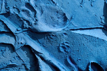 Téléchargez les photos : Décoratif fond de mastic bleu. Texture murale avec de la pâte de remplissage appliquée avec une spatule, des tirets chaotiques et des traits sur du plâtre. Conception créative, motif en pierre, hommes - en image libre de droit