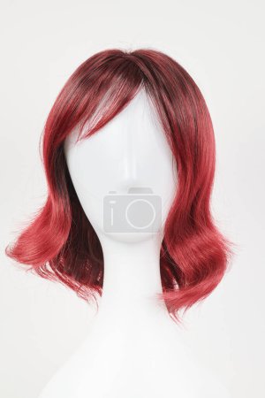 Téléchargez les photos : Perruque rouge naturelle sur tête de mannequin blanche. Cheveux de longueur moyenne sur le porte-perruque en plastique isolé sur fond blanc, vue de face - en image libre de droit