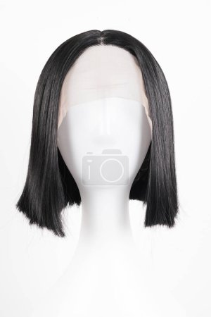 Téléchargez les photos : Perruque noire naturelle sur tête de mannequin blanche. Cheveux raides de longueur moyenne sur le porte-perruque métallique isolé sur fond blanc, vue de face - en image libre de droit