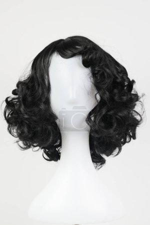 Photo for Natural looking black wig on white mannequin head. Medium length curly wavy hair on the metal wig holder isolated on white background, front view - Royalty Free Image