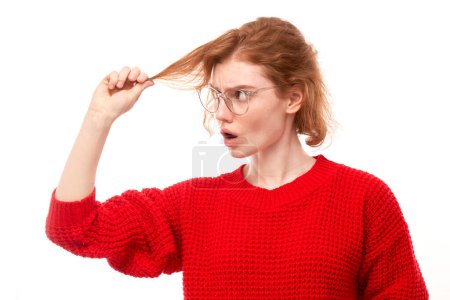 Photo for Portrait redhead young woman touching hair with displeased face isolated on white studio background, damaged hair concept - Royalty Free Image