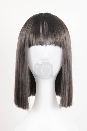 Photo for Natural looking black wig on white mannequin head. Medium length straight hair with bangs on the metal wig holder isolated on white background, front view - Royalty Free Image