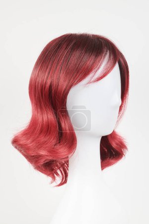 Photo for Natural looking red wig on white mannequin head. Medium length hair on the plastic wig holder isolated on white background, side view - Royalty Free Image