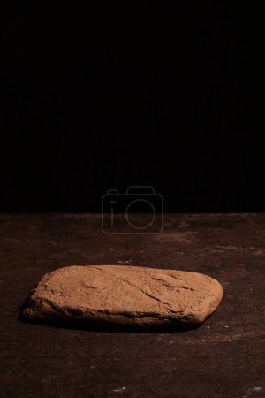 Foto de Pantalla de podio de piedra marrón sobre fondo negro, maqueta. Soporte decorativo texturizado para productos de belleza con spac de copia - Imagen libre de derechos