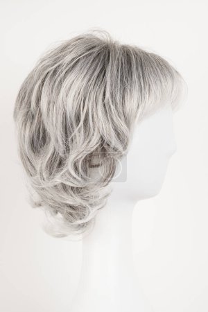 Photo for Natural looking silver blonde wig on white mannequin head. Short hair on the plastic wig holder isolated on white background, side view - Royalty Free Image