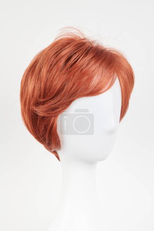 Photo for Natural looking ginger wig on white mannequin head. Short hair on the plastic wig holder isolated on white background, side vie - Royalty Free Image