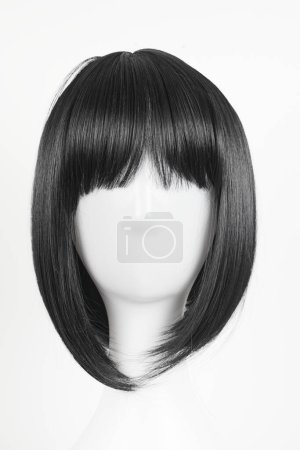 Photo for Natural looking black wig on white mannequin head. Medium length straight hair with bangs on the metal wig holder isolated on white background, front view - Royalty Free Image