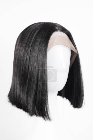 Photo for Natural looking black wig on white mannequin head. Medium length straight hair on the metal wig holder isolated on white background, side view - Royalty Free Image
