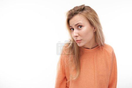 Photo for Portrait of young blond girl suspiciously looking at camera isolated on white studio background, squinting incredulousl - Royalty Free Image