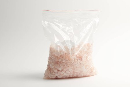 Foto de Piedra salada rosada del Himalaya astillada en bolsa de cremallera aislada sobre fondo blanco - Imagen libre de derechos