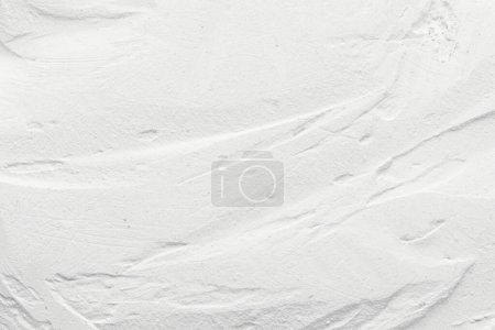 Téléchargez les photos : Décoratif fond de mastic blanc. Texture murale avec de la pâte de remplissage appliquée avec une spatule, des tirets chaotiques et des touches sur le plaste - en image libre de droit