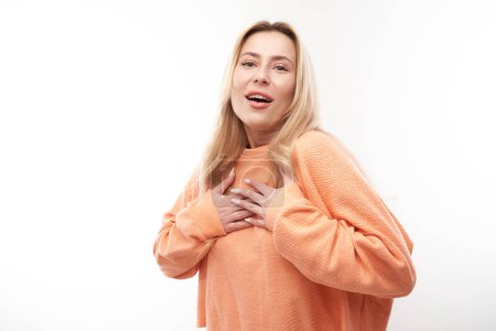 Photo for Portrait of young blond woman with kind expression put hands on her chest, feels gratitude and love isolated on white studio backgroun - Royalty Free Image