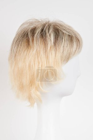 Photo for Natural looking blonde fair wig on white mannequin head. Short hair cut on the plastic wig holder isolated on white background, side vie - Royalty Free Image