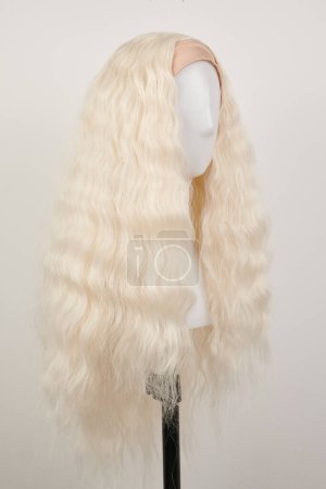 Foto de Peluca rubia de aspecto natural en la cabeza del maniquí blanco. Cabello largo en el soporte de peluca de plástico aislado en fondo blanco - Imagen libre de derechos
