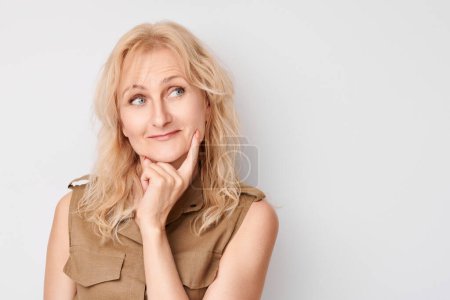 Photo for Portrait of clever mature woman touching chin thinking chooses doubts isolated on white studio background with copy spac - Royalty Free Image