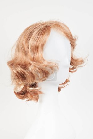 Foto de Peluca rubia de aspecto natural en la cabeza del maniquí blanco. Corte de pelo corto en el soporte de peluca de plástico aislado en fondo blanco - Imagen libre de derechos