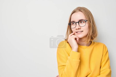 Photo for Clever blond student girl with glasses touch chin thinks, chooses isolated on white studio background with copy space. Confidence smart genius - Royalty Free Image