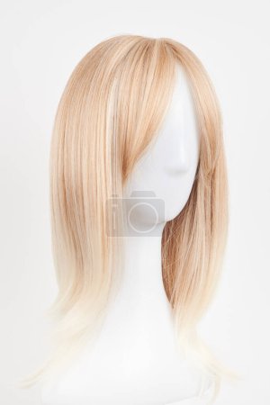 Photo for Natural looking blonde wig on white mannequin head. Long hair on the plastic wig holder isolated on white backgroun - Royalty Free Image