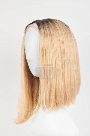 Photo for Natural looking blonde fair wig on white mannequin head. Middle length hair cut on the plastic wig holder isolated on white backgroun - Royalty Free Image
