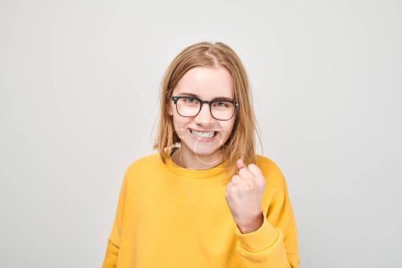 Photo for Portrait of angry schoolgirl yelling clenching fists isolated on white studio background. Devil face. Human emotions, facial expression concept - Royalty Free Image