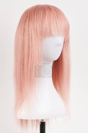 Foto de Peluca rubia rosa de aspecto natural en la cabeza del maniquí blanco. Corte de pelo largo en el soporte de peluca de plástico aislado sobre fondo blanco - Imagen libre de derechos