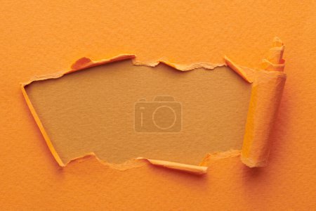 Photo for Frame of ripped paper with torn edges. Window for text with copy space orange brown colors, shreds of notebook pages. Abstract backgroun - Royalty Free Image