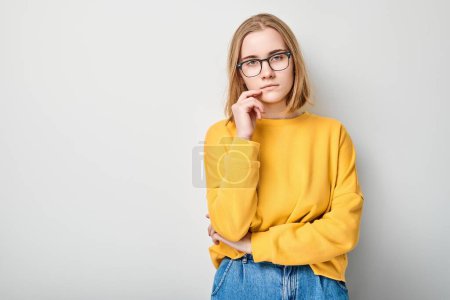Photo for Clever blond student girl with glasses touch chin thinks, chooses isolated on white studio background with copy space. Confidence smart genius - Royalty Free Image