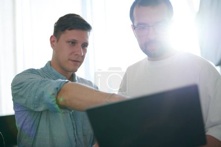 Téléchargez les photos : Portrait de deux programmeurs professionnels de sexe masculin travaillant sur ordinateur dans divers bureaux. Technologies informatiques modernes, développement de l'intelligence artificielle, programmes, applications et concept de jeux vidéo - en image libre de droit