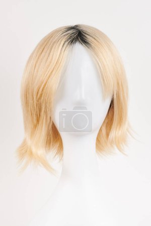 Photo for Natural looking blonde fair wig on white mannequin head. Short hair cut on the plastic wig holder isolated on white background, front vie - Royalty Free Image