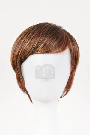 Natural looking dark brunet wig on white mannequin head. Short brown hair on the plastic wig holder isolated on white background, front view 