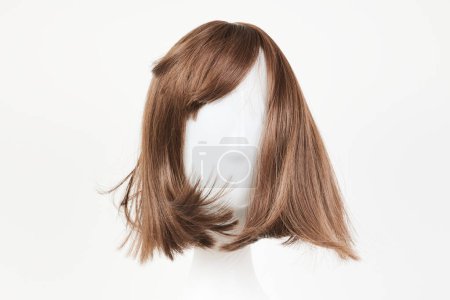 Photo for Natural looking dark brunet wig on white mannequin head. Middle length brown hair on the plastic wig holder isolated on white background, front view - Royalty Free Image