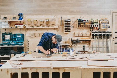 Téléchargez les photos : Charpentier travaille avec du bois dans un atelier de menuiserie. Homme faisant de la menuiserie professionnellement - en image libre de droit