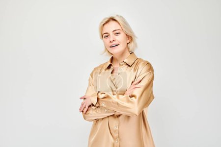 Téléchargez les photos : Portrait Femme blanche jeune blonde souriante joyeusement isolée sur fond de studio blanc. Fille heureuse en chemise de soie beige avec expression de visage heureux - en image libre de droit