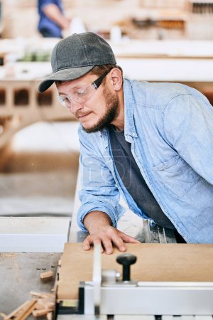 Foto de Carpintero trabaja con madera en taller de carpintería. Hombre haciendo carpintería profesionalmente - Imagen libre de derechos