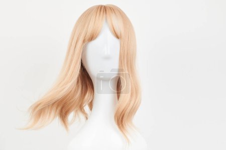 Téléchargez les photos : Perruque blonde blonde naturelle sur tête de mannequin blanche. Cheveux mi-longs coupés sur le porte-perruque en plastique isolé sur fond blanc, front vie - en image libre de droit