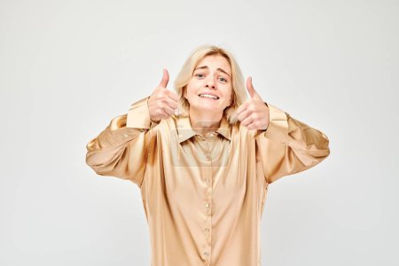 Foto de Retrato de una joven rubia vestida con ropa casual sonriendo alegremente mostrando el gesto de los pulgares hacia arriba aislado en el fondo blanco del estudio. Aprueba la buena elección, la decisión correcta - Imagen libre de derechos
