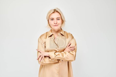 Photo for Portrait Caucasian young blond woman smiling joyfully isolated on white studio background. Happy girl in beige silk shirt with glad face expression - Royalty Free Image