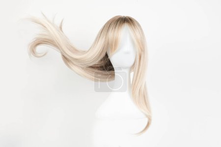 Foto de Peluca rubia de aspecto natural en la cabeza del maniquí blanco. Cabello largo en el soporte de peluca de plástico aislado sobre fondo blanco, frente vie - Imagen libre de derechos