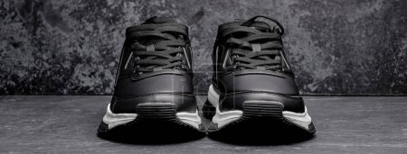 Téléchargez les photos : Baskets homme en cuir noir isolé sur fond grunge noir, chaussures de sport - en image libre de droit
